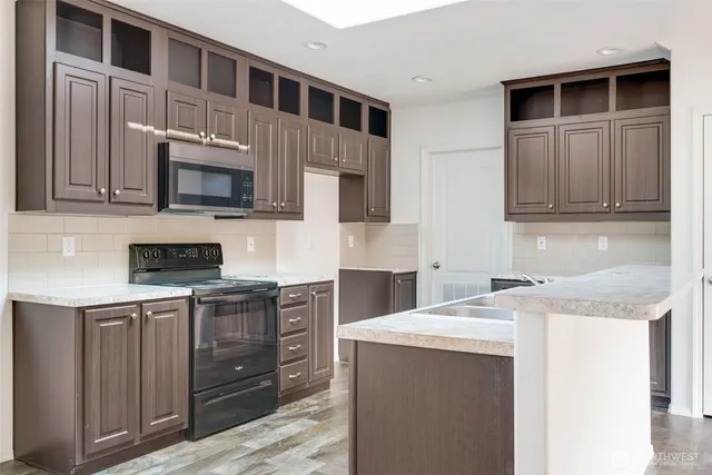 a kitchen with stainless steel appliances granite countertop a stove microwave and sink