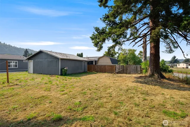 a backyard of a house with large trees and wooden fence