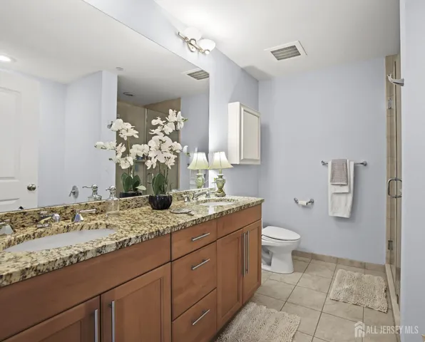 a bathroom with a granite countertop sink a toilet and a mirror