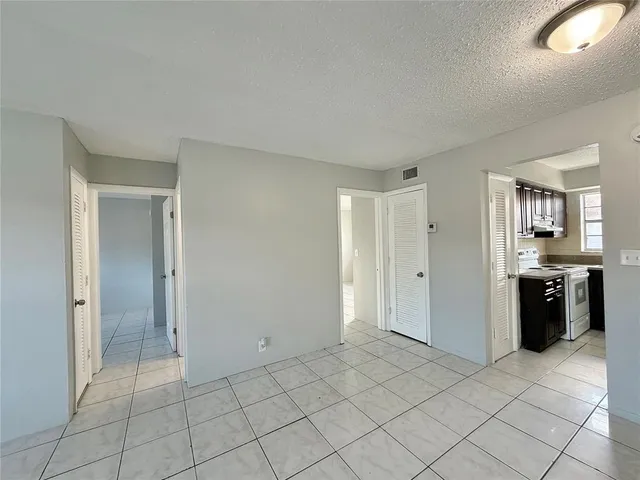 an empty room with kitchen and entryway