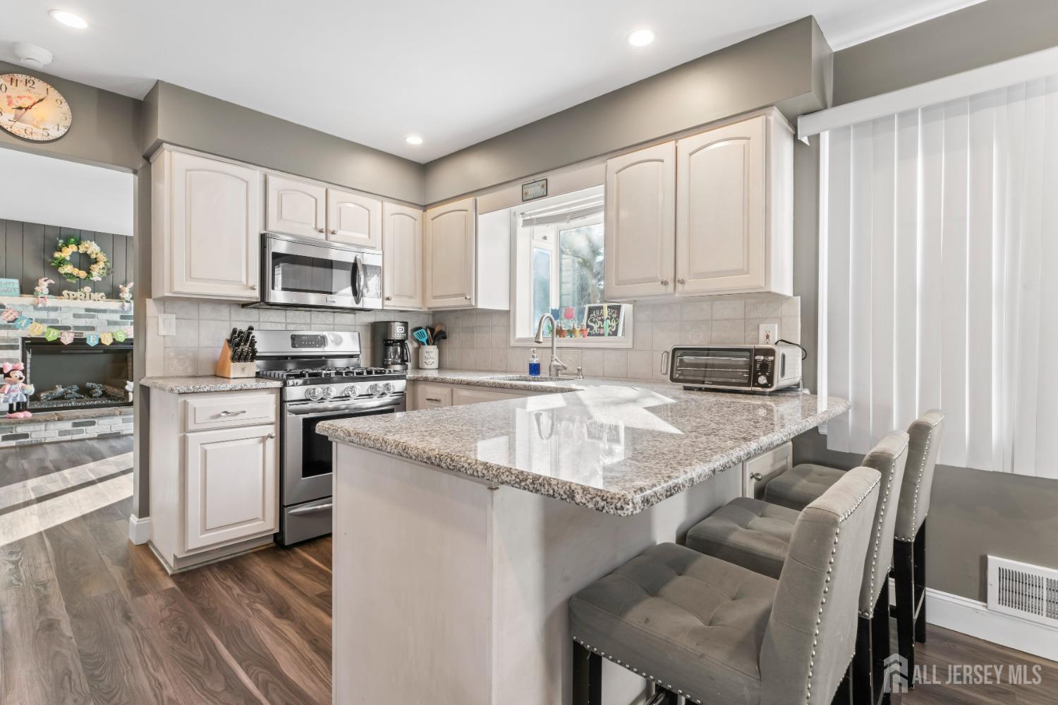 4 Whitman Road Morganville, NJ 07751 - Photo 12 of 45 a kitchen with stainless steel appliances granite countertop a sink a stove a refrigerator cabinets and a dining table with wooden floor