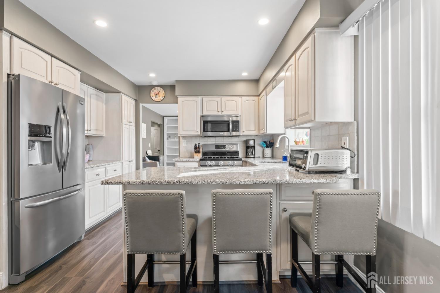 4 Whitman Road Morganville, NJ 07751 - Photo 10 of 45 a kitchen with stainless steel appliances granite countertop a dining table chairs refrigerator and microwave