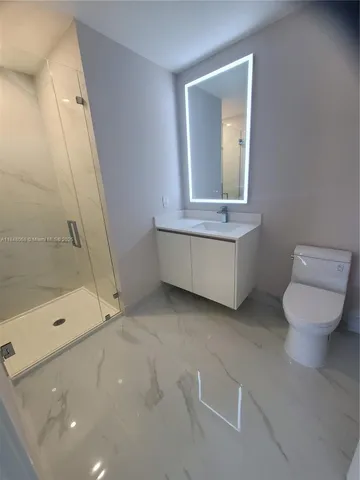 a bathroom with a granite countertop sink a toilet and shower