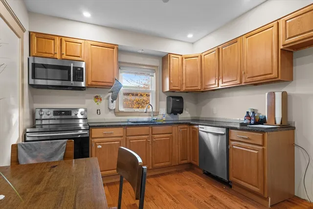 a kitchen with stainless steel appliances granite countertop a stove top oven a sink dishwasher and cabinets with wooden floor