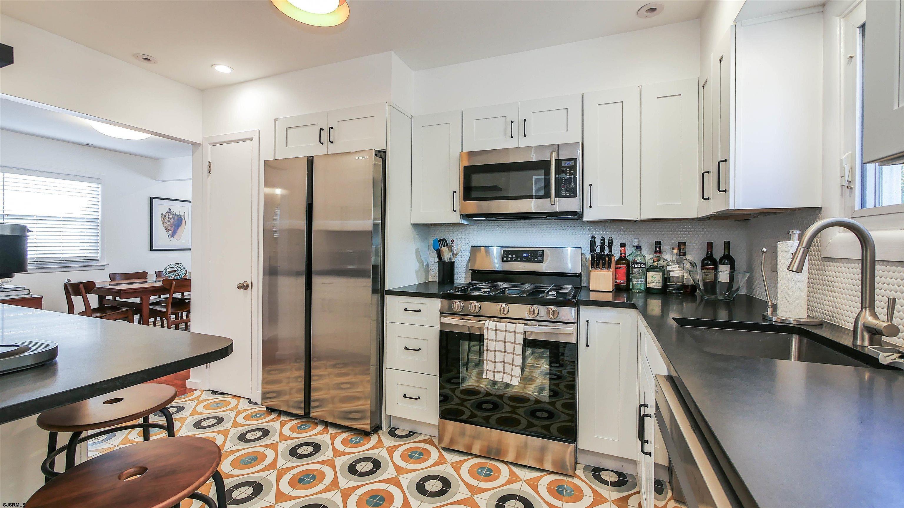12 North Delavan Avenue, Unit AUGUST 1ST LABOR DAY 2026 Margate City, NJ 08402 - Photo 11 of 41 a kitchen with stainless steel appliances granite countertop a sink a stove a refrigerator cabinets and chairs