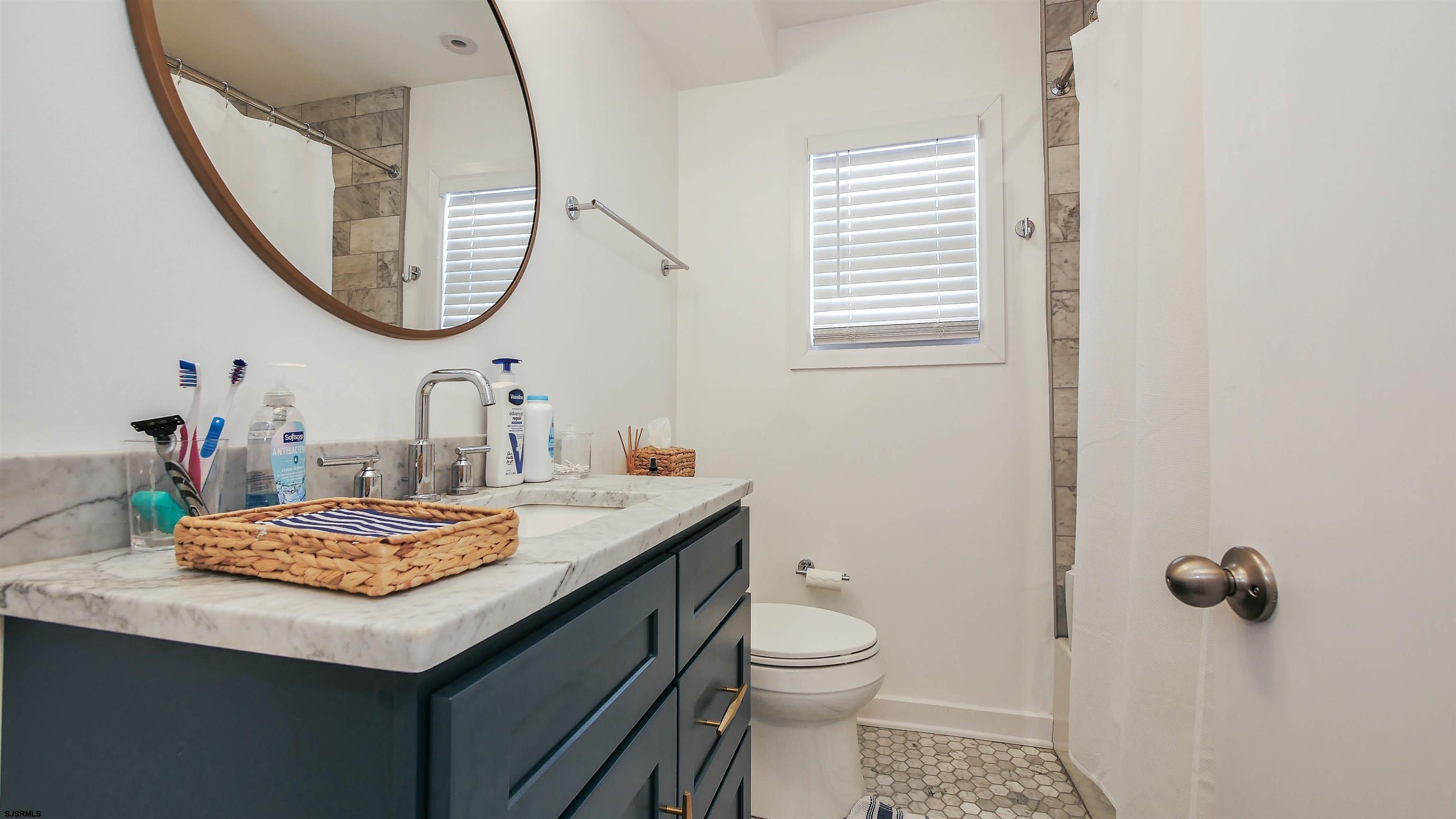 12 North Delavan Avenue, Unit AUGUST 1ST LABOR DAY 2026 Margate City, NJ 08402 - Photo 13 of 41 a bathroom with a sink a toilet and a mirror