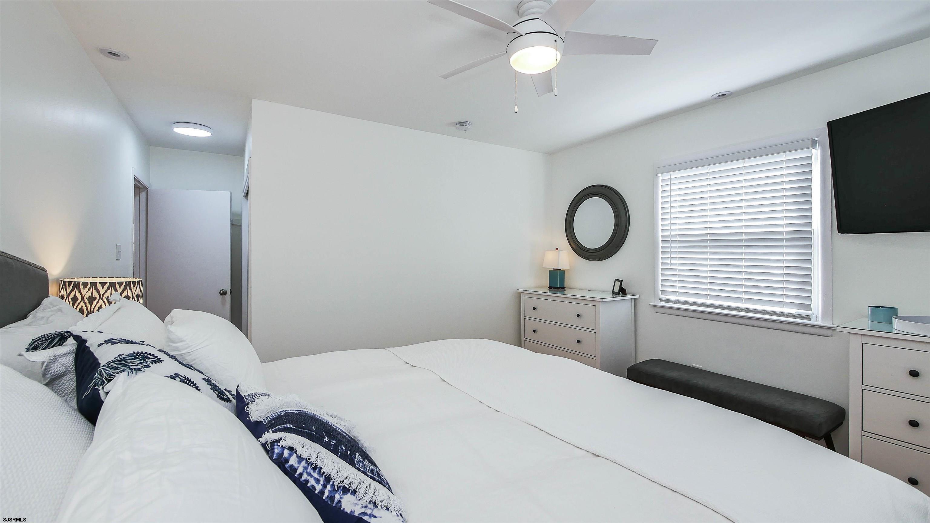12 North Delavan Avenue, Unit AUGUST 1ST LABOR DAY 2026 Margate City, NJ 08402 - Photo 18 of 41 a bedroom with a large bed and a flat tv screen on dresser