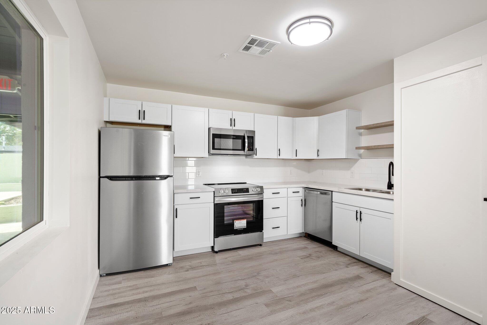 3114 North 68th Street, Unit 2 Scottsdale, AZ 85251 - Photo 16 of 25 a kitchen with cabinets stainless steel appliances and wooden floor