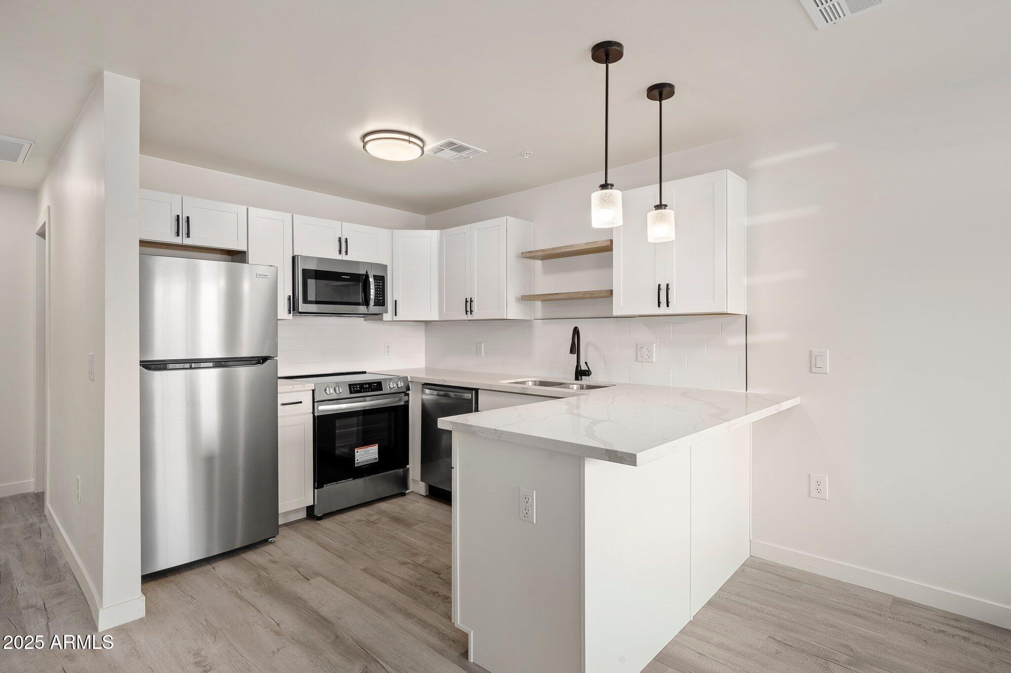 3114 North 68th Street, Unit 2 Scottsdale, AZ 85251 - Photo 21 of 25 a kitchen with kitchen island a sink stainless steel appliances and refrigerator