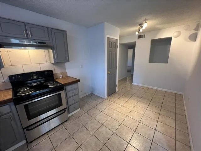 en empty room with windows and chandelier fan