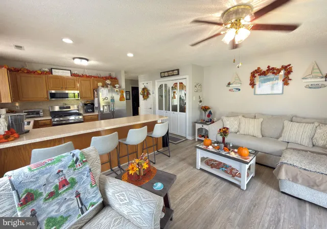 a living room with furniture kitchen view and a wooden floor