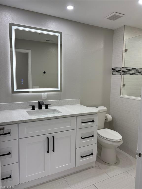 7940 Preserve Circle, Unit 914 Naples, FL 34119 - Photo 6 of 16 a bathroom with a granite countertop toilet sink vanity and mirror