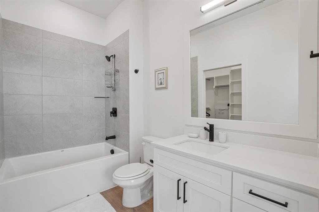 6418 Maple Avenue, Unit 312 Dallas, TX 75235 - Photo 12 of 16 a bathroom with a bathtub shower sink mirror vanity and toilet