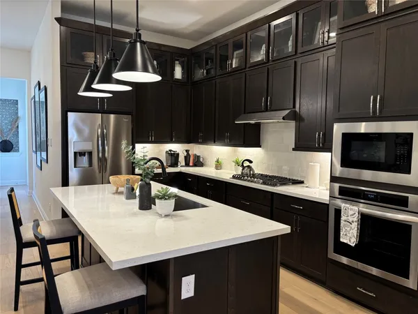 a kitchen with stainless steel appliances a stove a sink dishwasher and cabinets with wooden floor