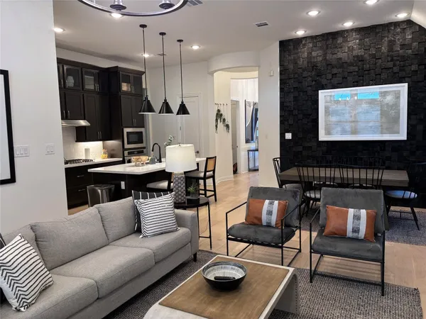 a living room with furniture a flat screen tv and a chandelier