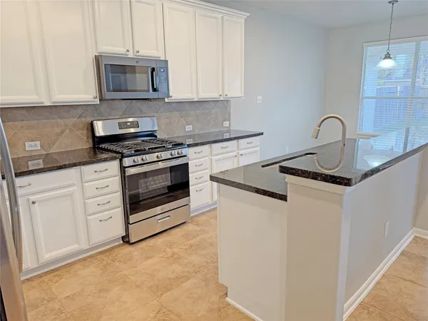 a kitchen with stainless steel appliances granite countertop a stove a sink and a microwave