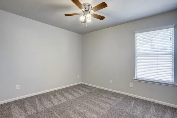 an empty room with a window and a fan