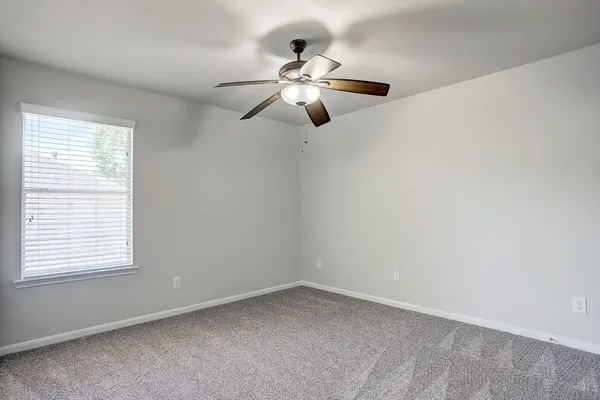 an empty room with a window and a fan
