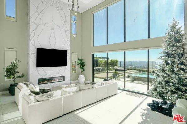 a living room with furniture a flat screen tv and a floor to ceiling window