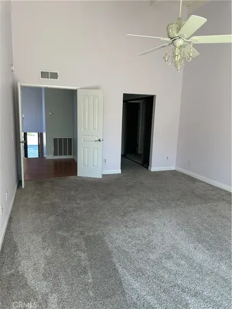 a view of an empty room with a chandelier fan