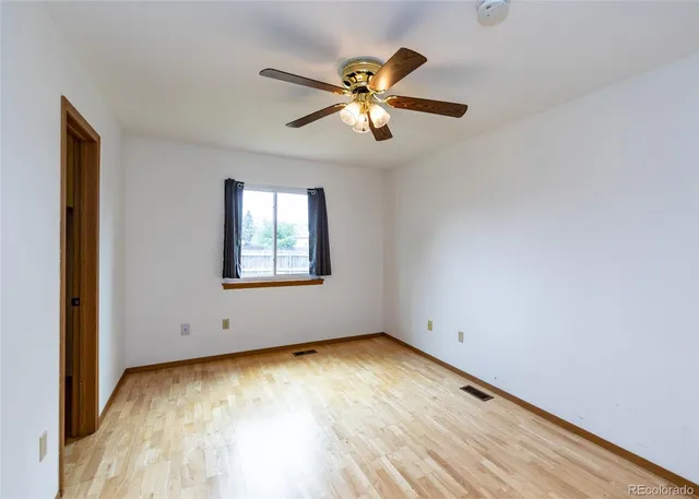 an empty room with a window and ceiling fan
