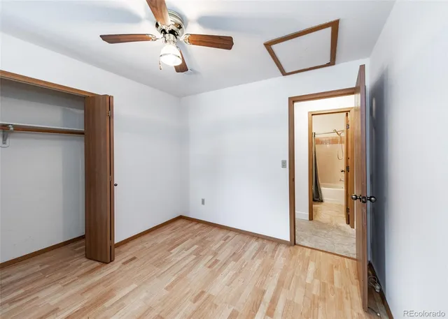an empty room with wooden floor chandelier fan and windows