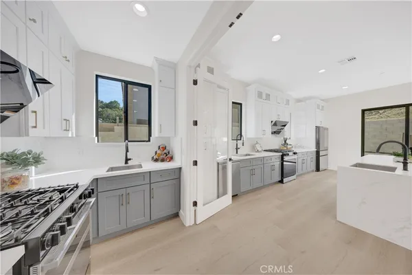 a large white kitchen with stainless steel appliances granite countertop a lot of white cabinets