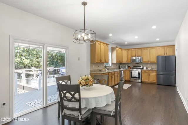 a dining room with wooden floor a chandelier a wooden table and chairs