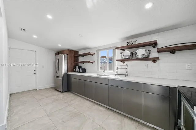 a room with stainless steel appliances kitchen island granite countertop a sink and cabinets
