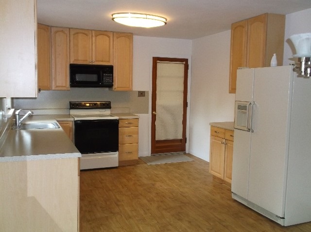 265 Fairgrounds Road Farmville, VA 23901 - Photo 5 of 14 a kitchen with stainless steel appliances a stove a microwave a sink a refrigerator white cabinets and wooden floor
