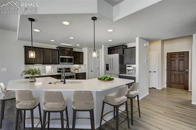 a kitchen with stainless steel appliances kitchen island granite countertop a dining table chairs and white cabinets