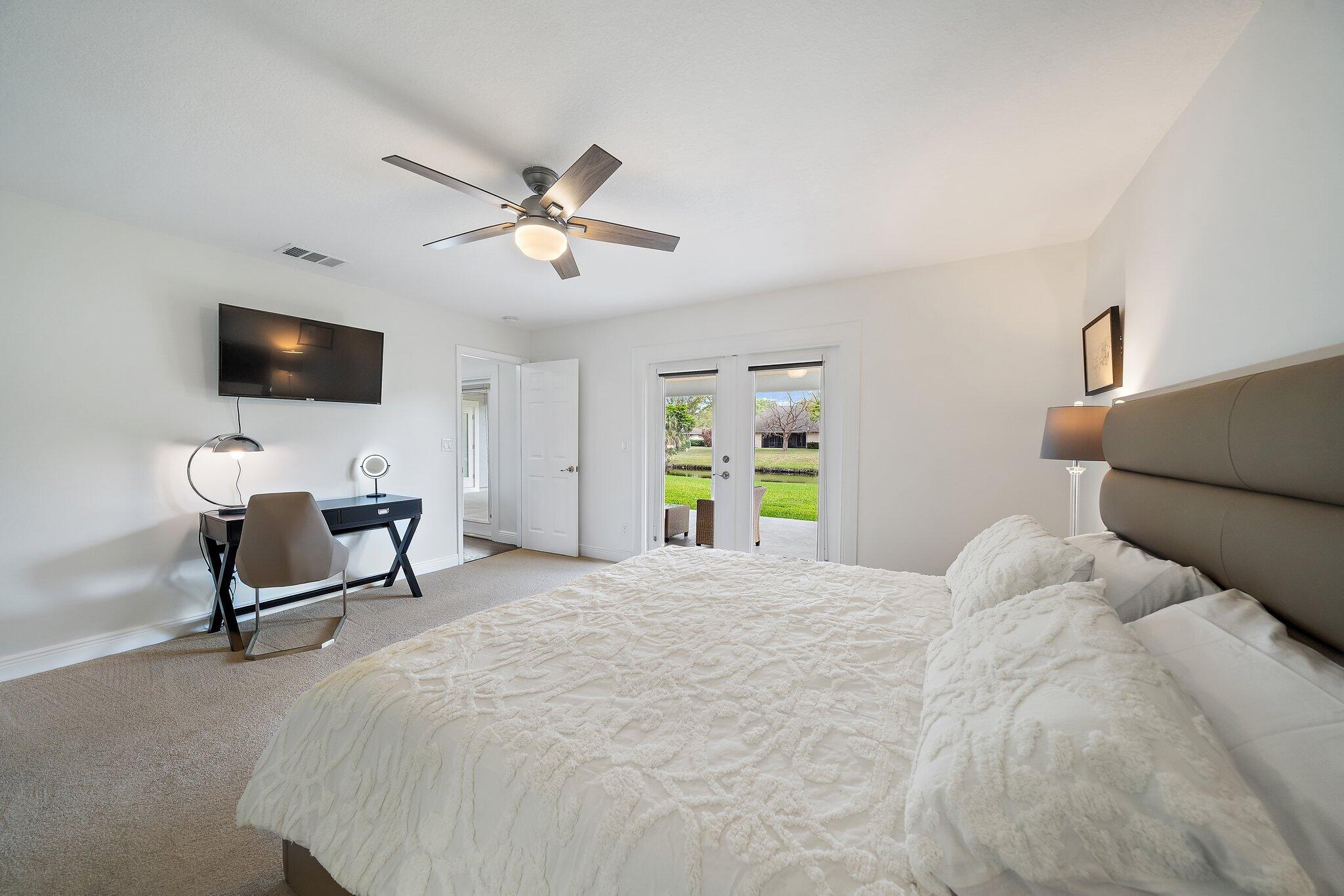 1342 Essex Drive Wellington, FL 33414 - Photo 15 of 58 a bedroom with a bed a window and a flat screen tv