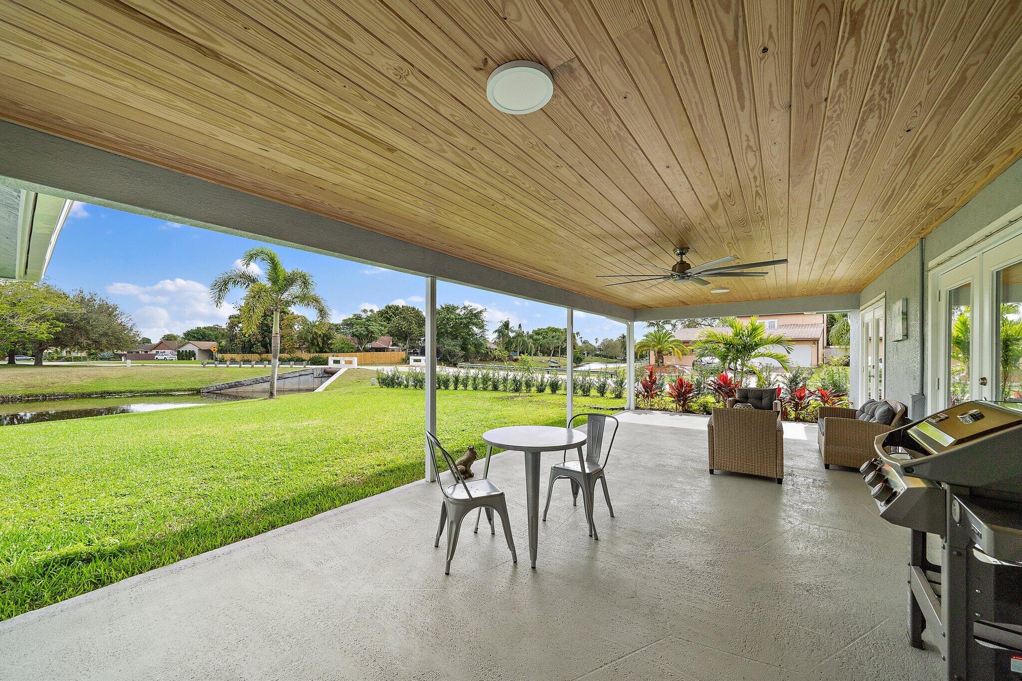 1342 Essex Drive Wellington, FL 33414 - Photo 48 of 58 a view of a patio with couches chairs and a big yard