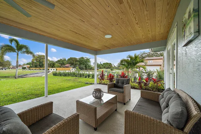 a view of a patio with table and chairs potted plants and floor to ceiling window