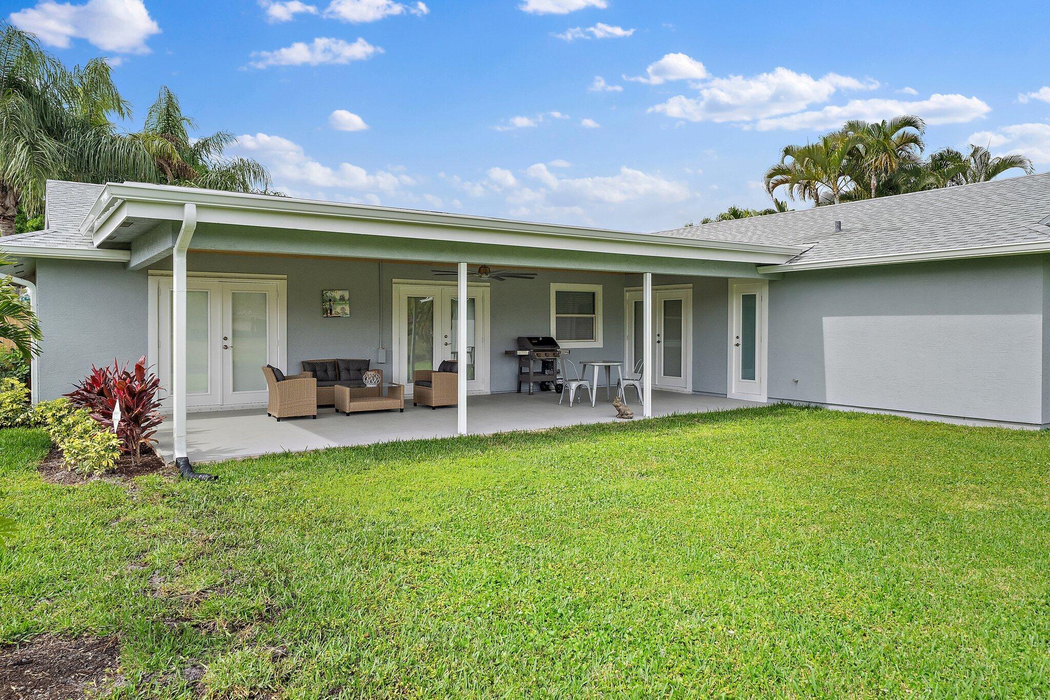 1342 Essex Drive Wellington, FL 33414 - Photo 57 of 58 a view of a patio with table and chairs potted plants and floor to ceiling window