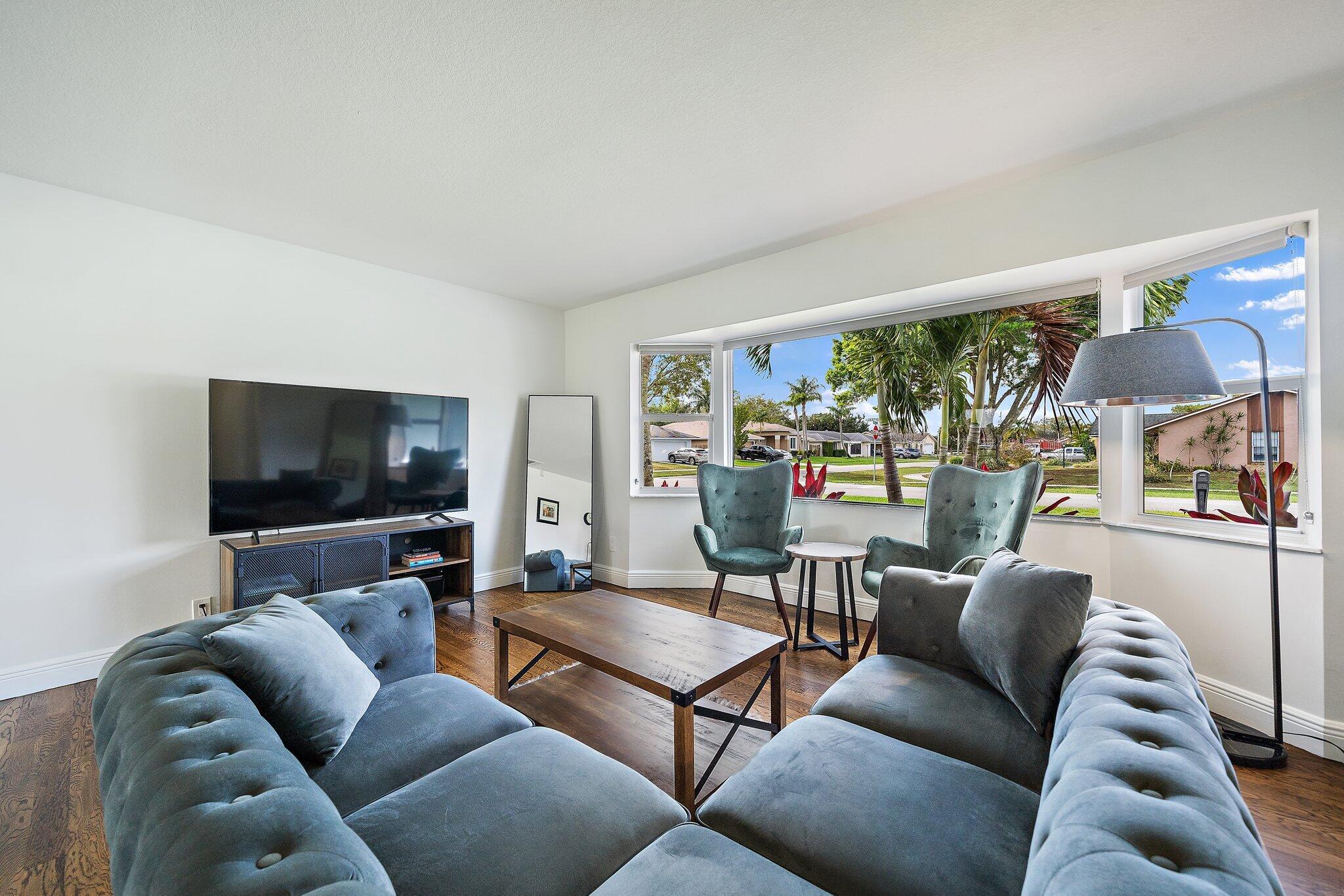 1342 Essex Drive Wellington, FL 33414 - Photo 7 of 58 a living room with furniture a flat screen tv and a floor to ceiling window