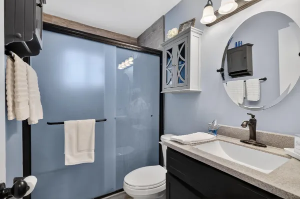 a bathroom with a granite countertop sink a toilet and mirror