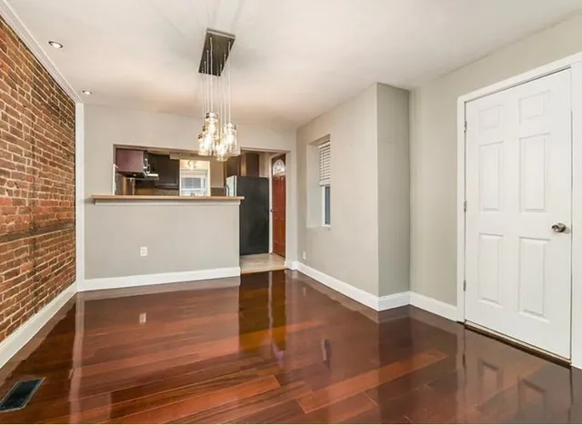 a view of a livingroom with wooden floor and kitchen space