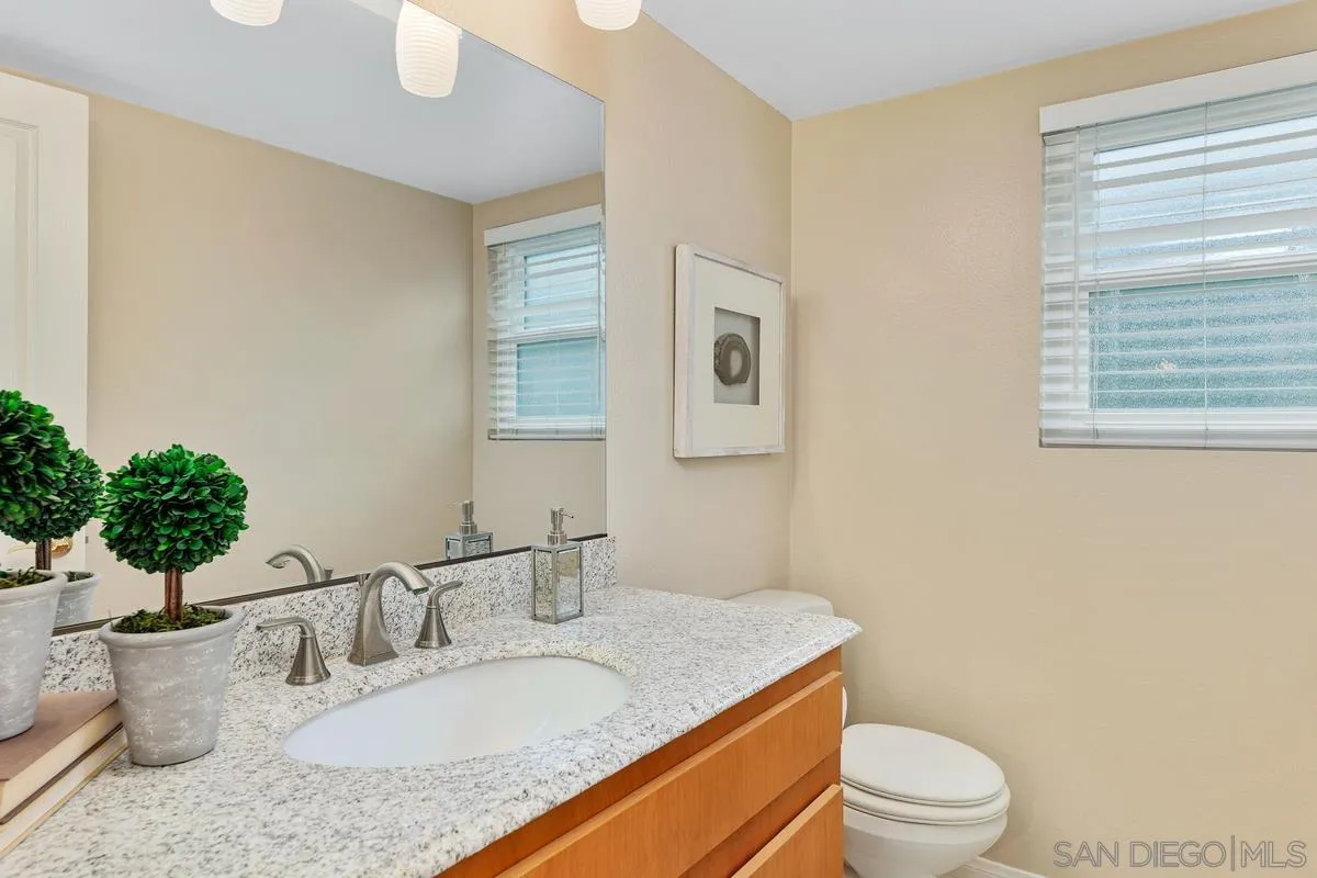 505 Willowspring Drive North Encinitas, CA 92024 - Photo 19 of 47 a bathroom with a granite countertop sink a toilet and a mirror