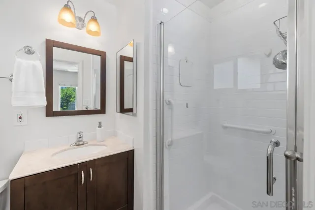 a bathroom with a shower sink vanity and mirror