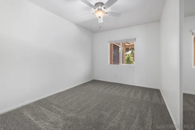 an empty room with a window and a fan