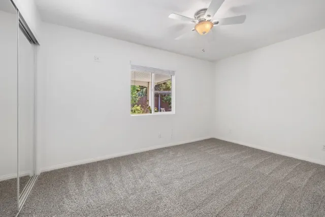 an empty room with a window and a ceiling fan