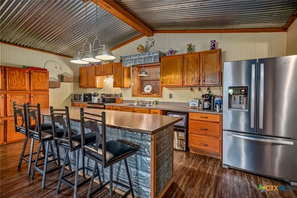 a kitchen with stainless steel appliances granite countertop a stove a refrigerator and a dining table with wooden floors