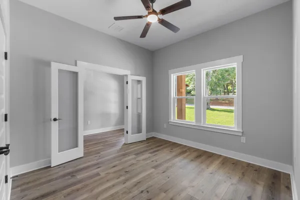 a view of an empty room with wooden floor and a window