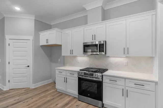 a view of a kitchen with stainless steel appliances granite countertop wooden floors sink and window