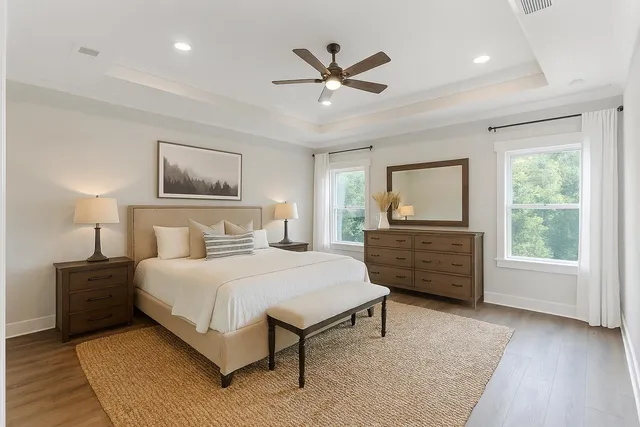 a view of an empty room with wooden floor and a ceiling fan