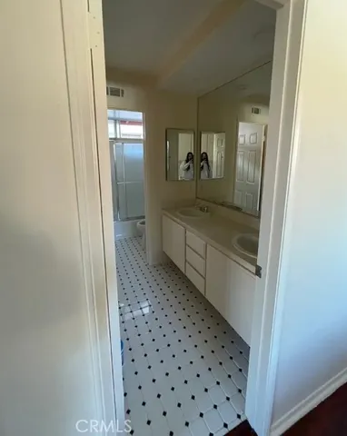 a bathroom with a glass door shower a sink and a toilet