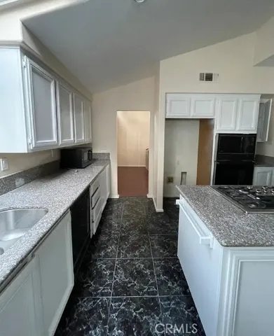 a kitchen with granite countertop a sink stove and cabinets