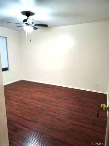 a view of a room with wooden floor and a ceiling fan