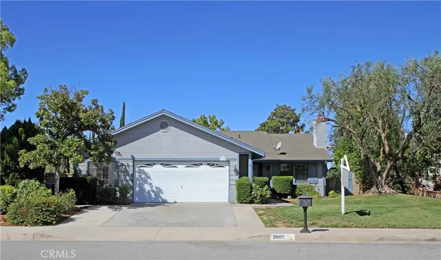 a front view of a house with a garden and trees